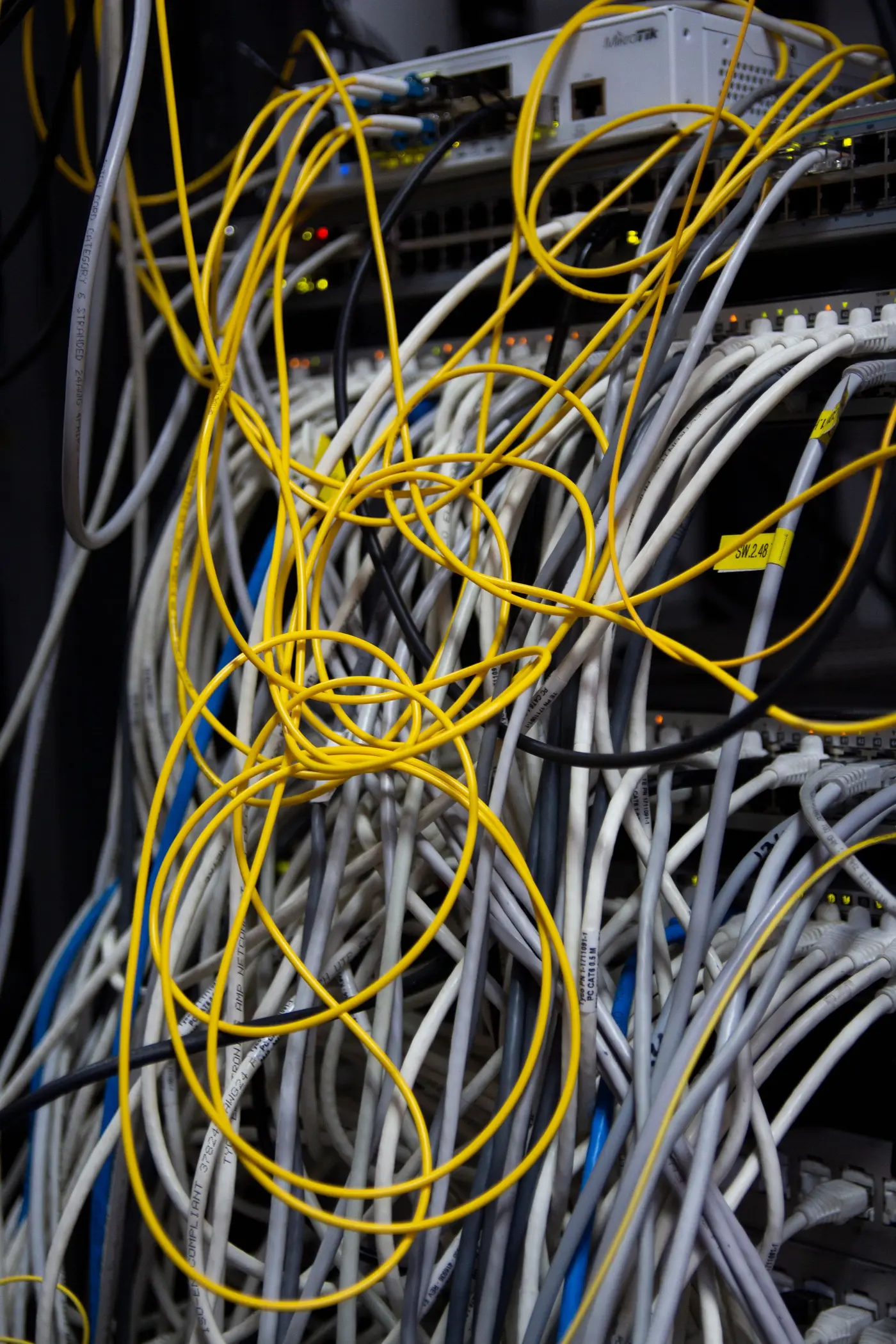 A tangle of yellow and gray network cables in an older rack