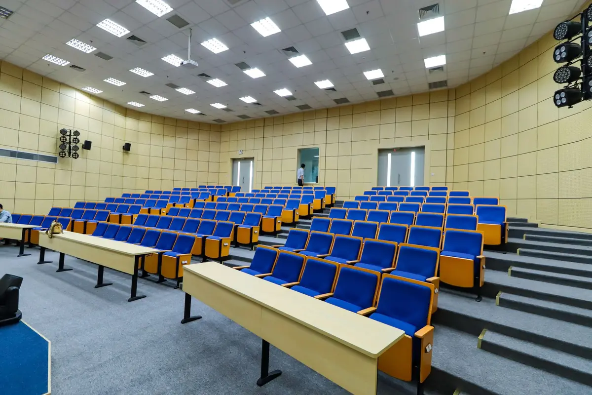 An empty lecture hall with rows of blue seats