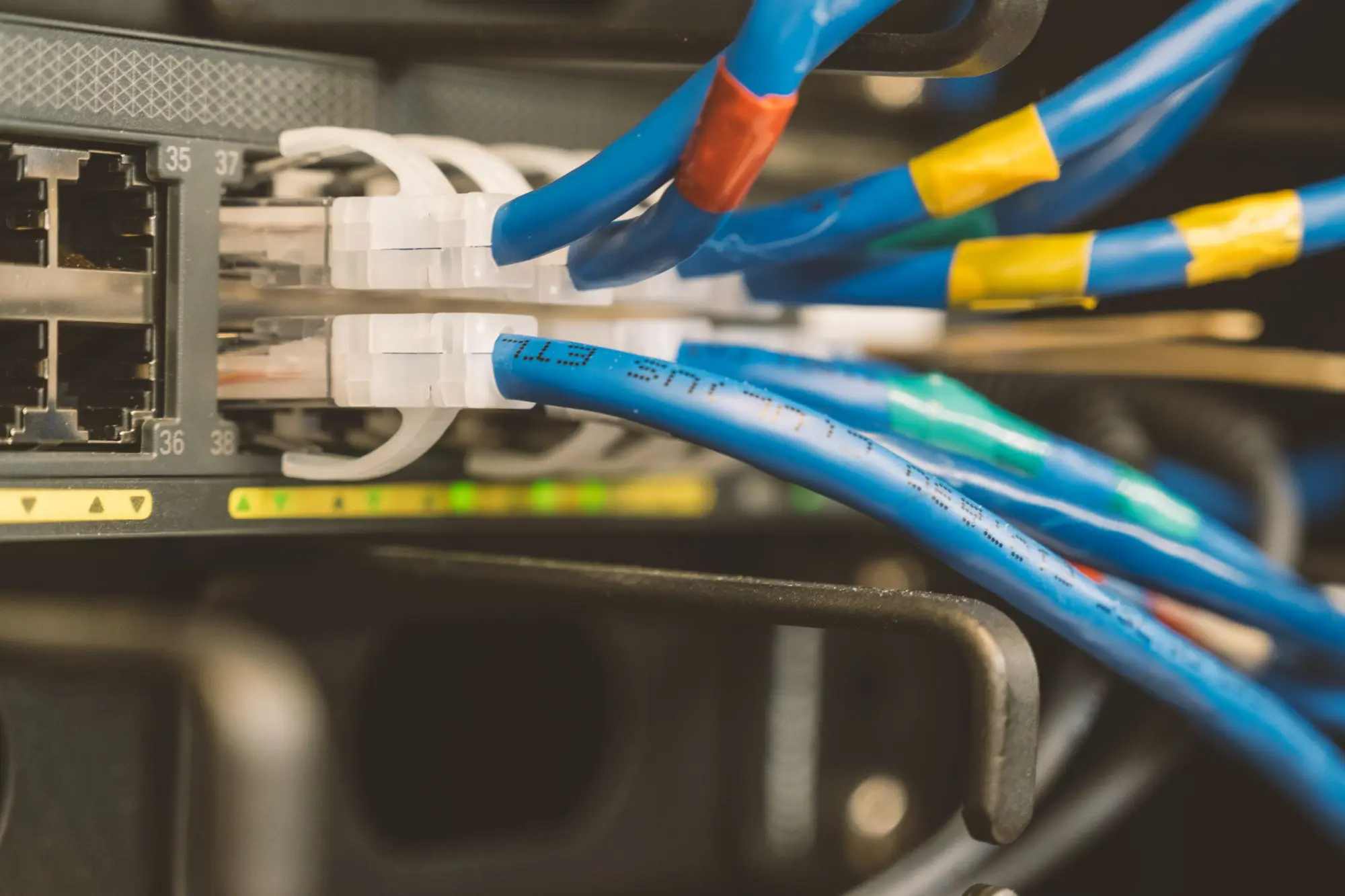 Blue patch cables with colored tape markers plugged into a switch